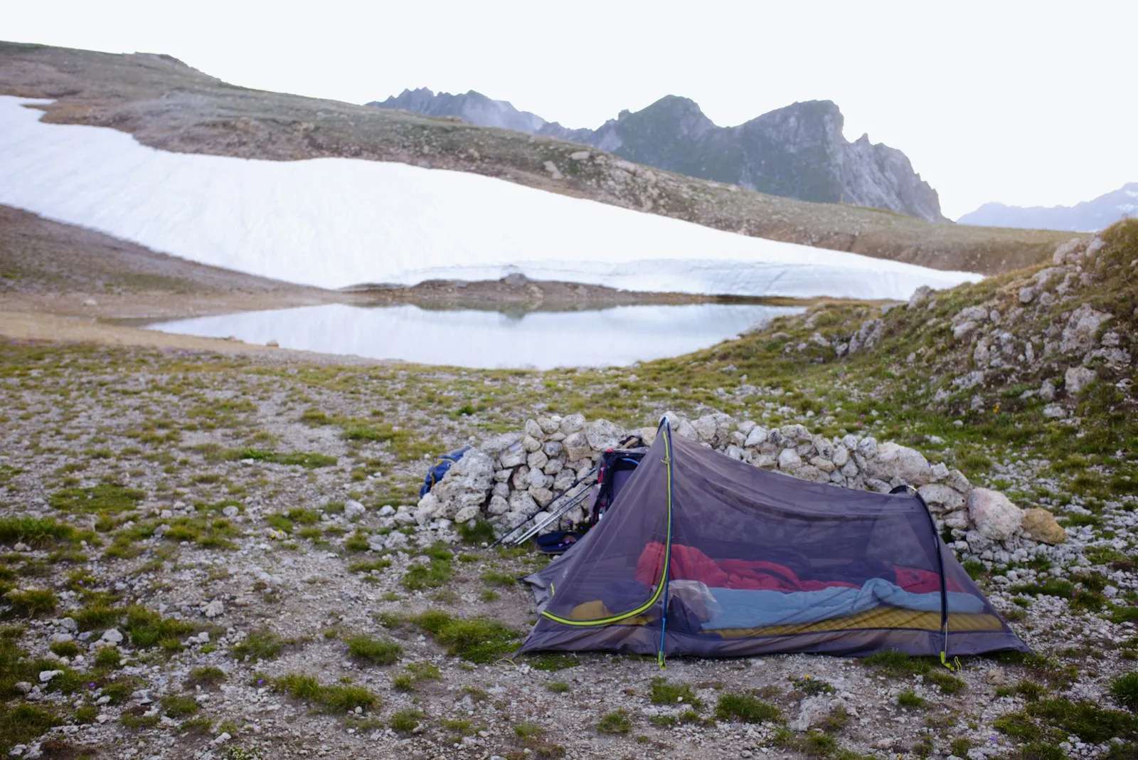 Petite tente de bivouac au bord d'un lac de montagne au lever du jour