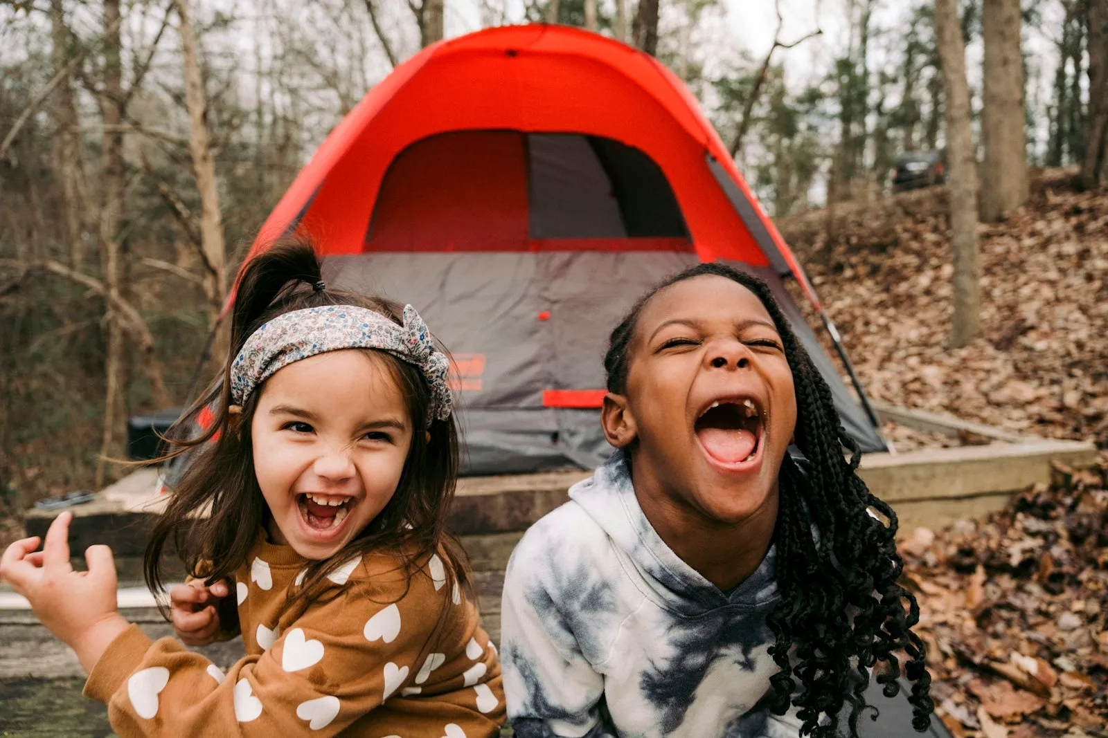 Famille installant une tente de camping dans un pré, enfants qui jouent