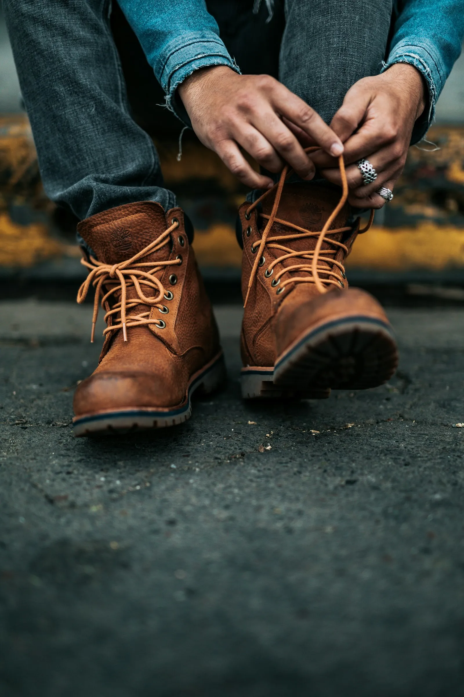 Une personne accroupie lace ses chaussures de marche montantes, vue de près sur les lacets et la tige
