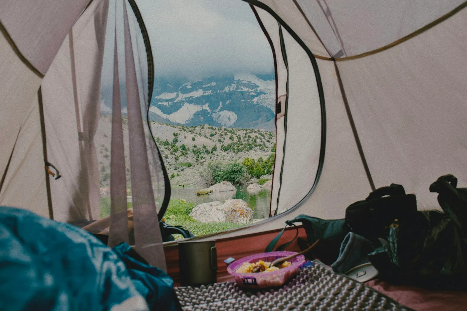 Matelas de camping déroulé dans une tente ouverte sur la nature