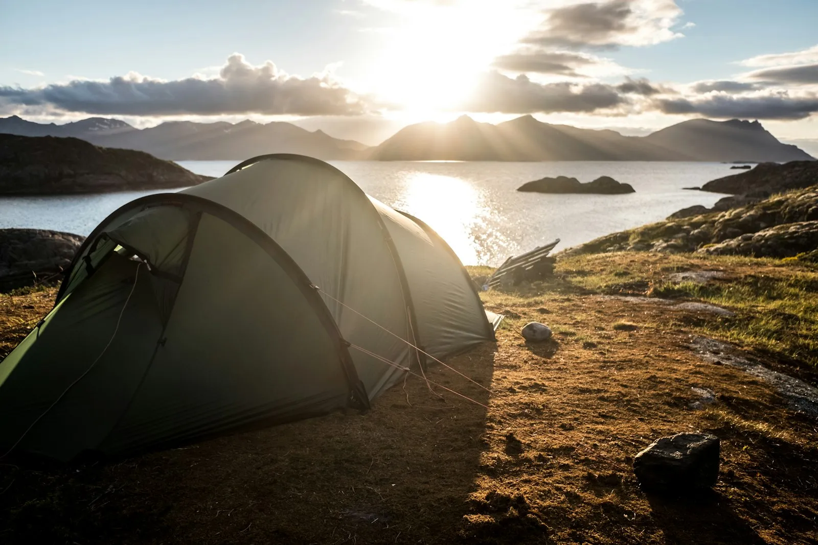 Tente de bivouac au bord d'un lac d'altitude dans les Alpes, au lever du soleil
