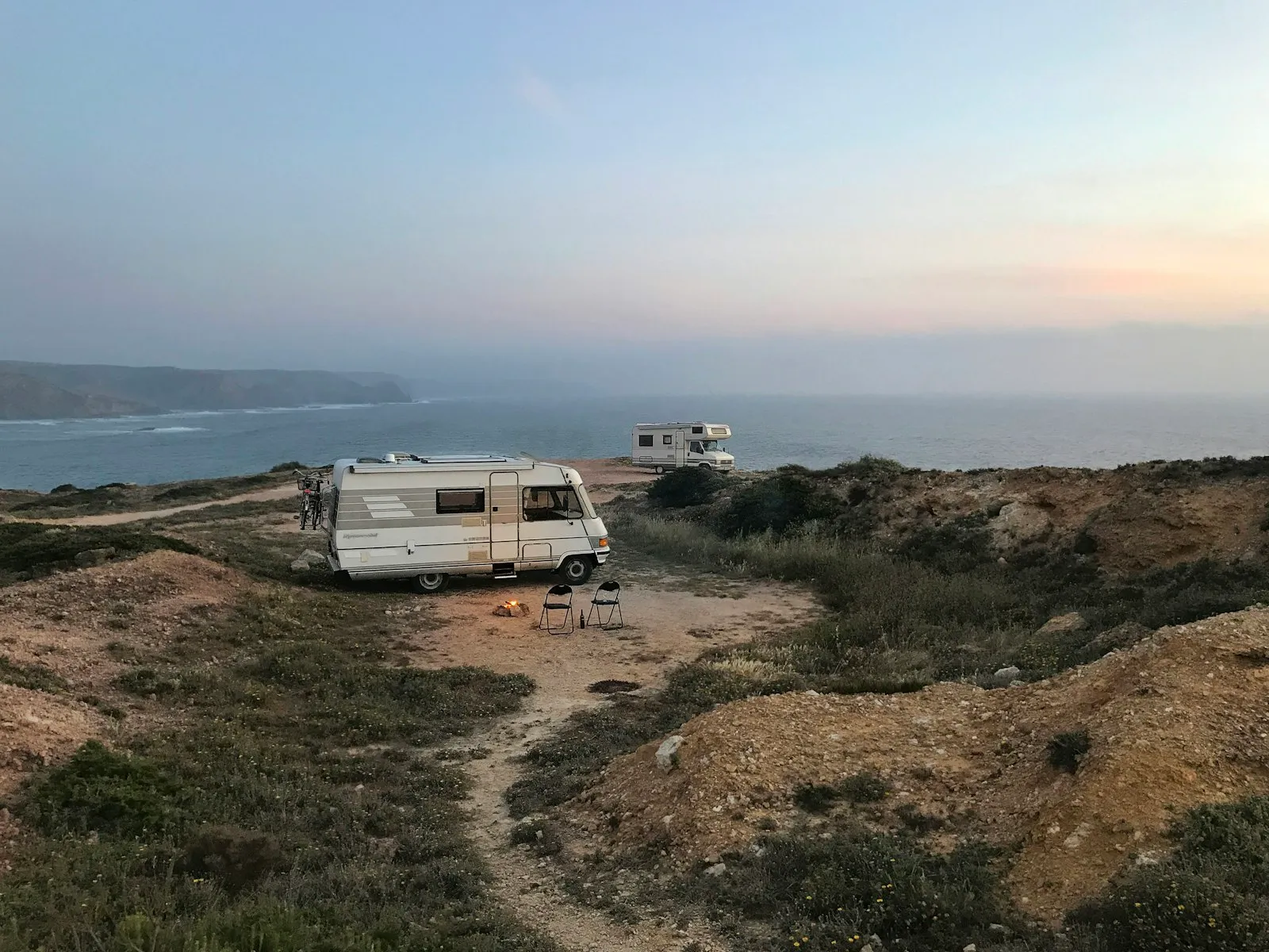 Van aménagé garé face à un paysage côtier au coucher du soleil