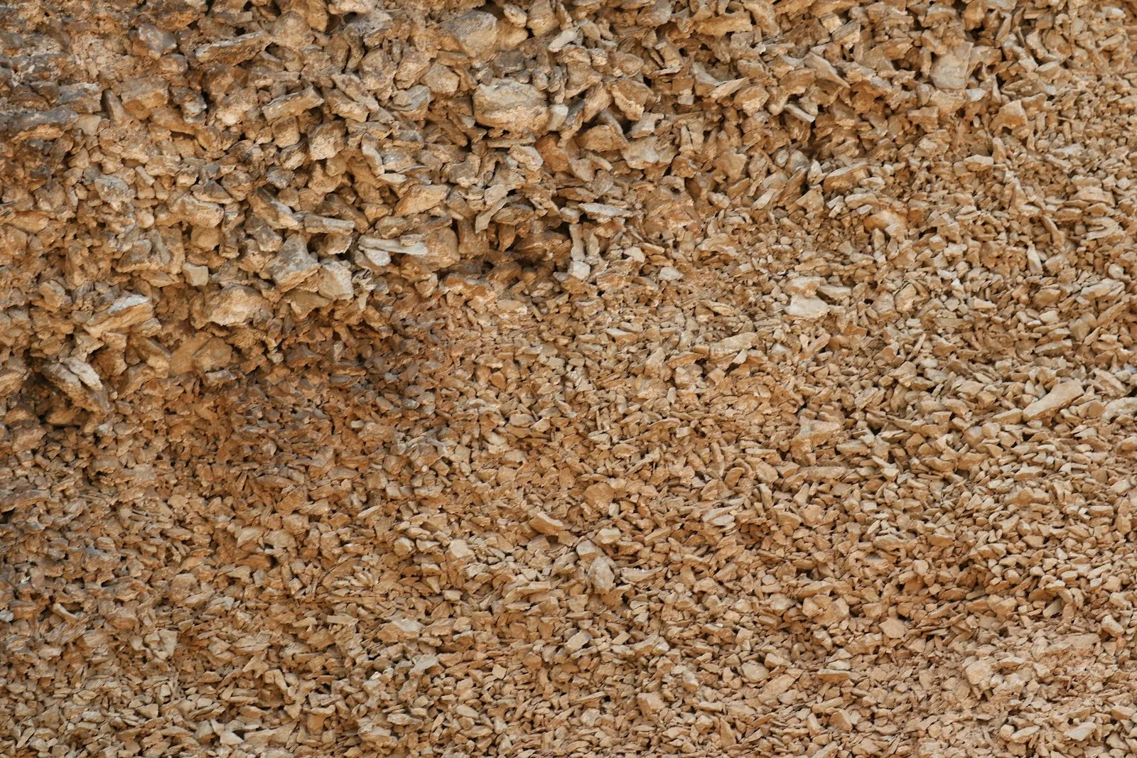 Amas de petits fragments beige et brun, gros morceaux en haut et éclats plus fins en bas, vus de près